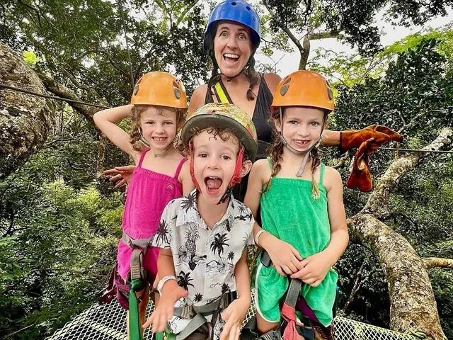 Guests in helmets gather together at a forest platform.