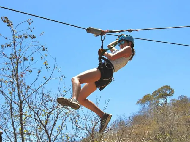 A guest rides a zipline above the treetops.